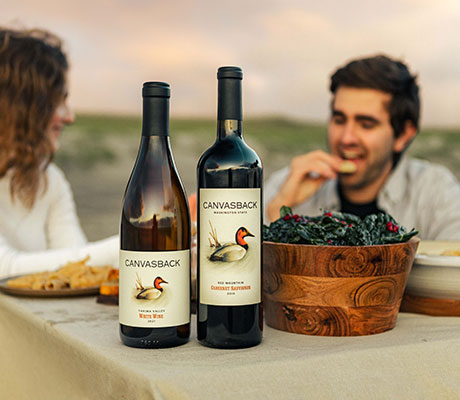Couple enjoying a beach picnic with Canvasback wines on the table