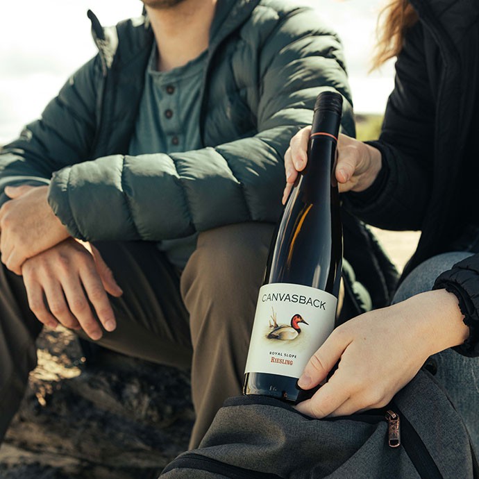 Two hikers pulling out a bottle of Canvasback wine