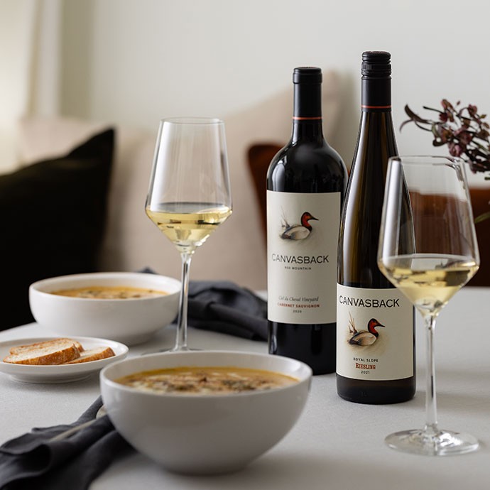 Canvasback wines on the table with bowls of soup