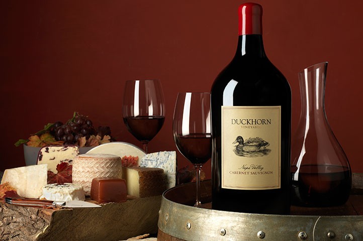 Large format Duckhorn Portfolio wine on a barrel with cheese and decanter